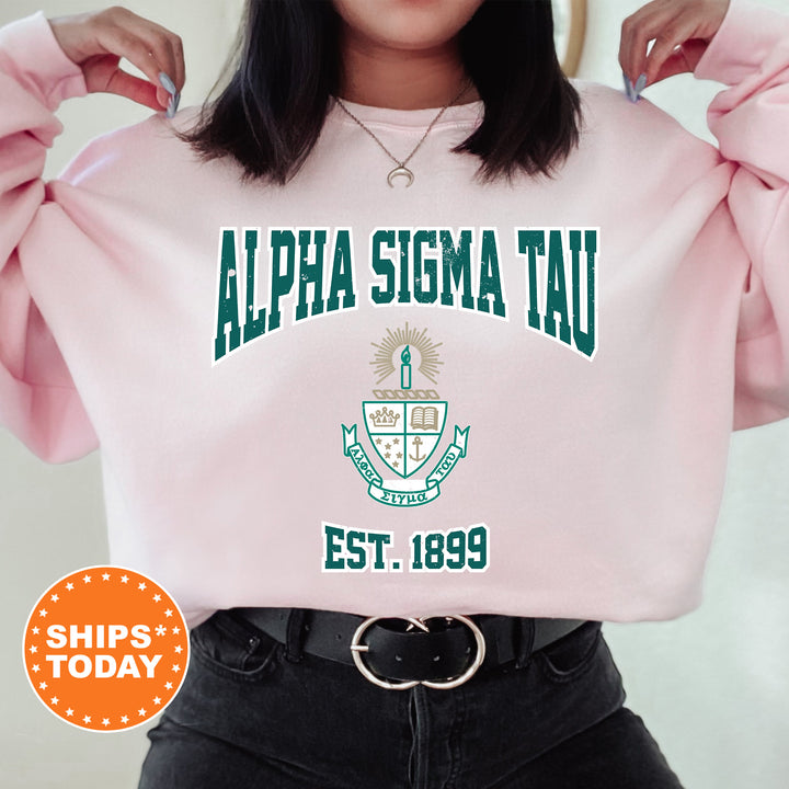 a woman wearing a pink sweatshirt with the words alpha sima tau on it