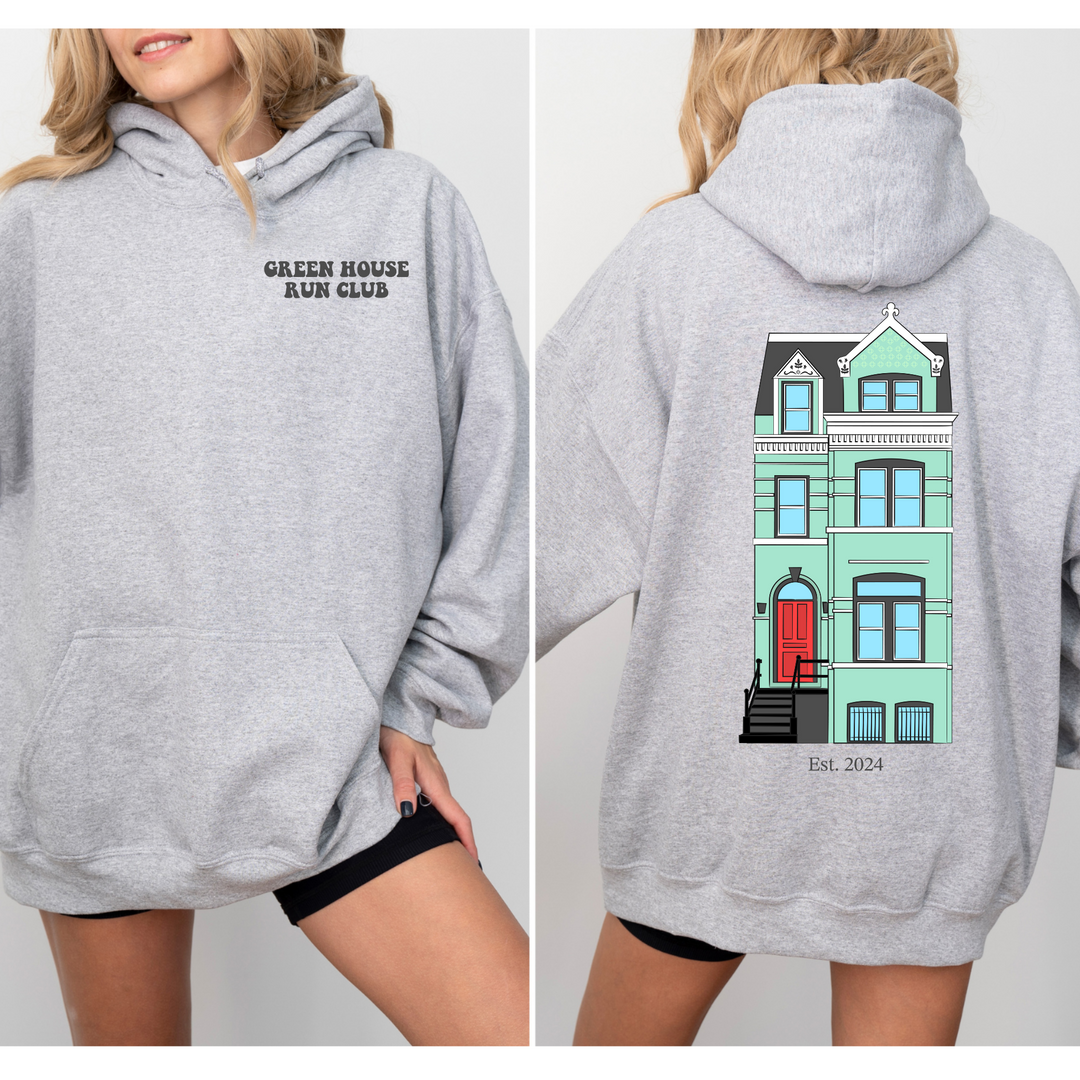 a woman wearing a grey sweatshirt with a house on it