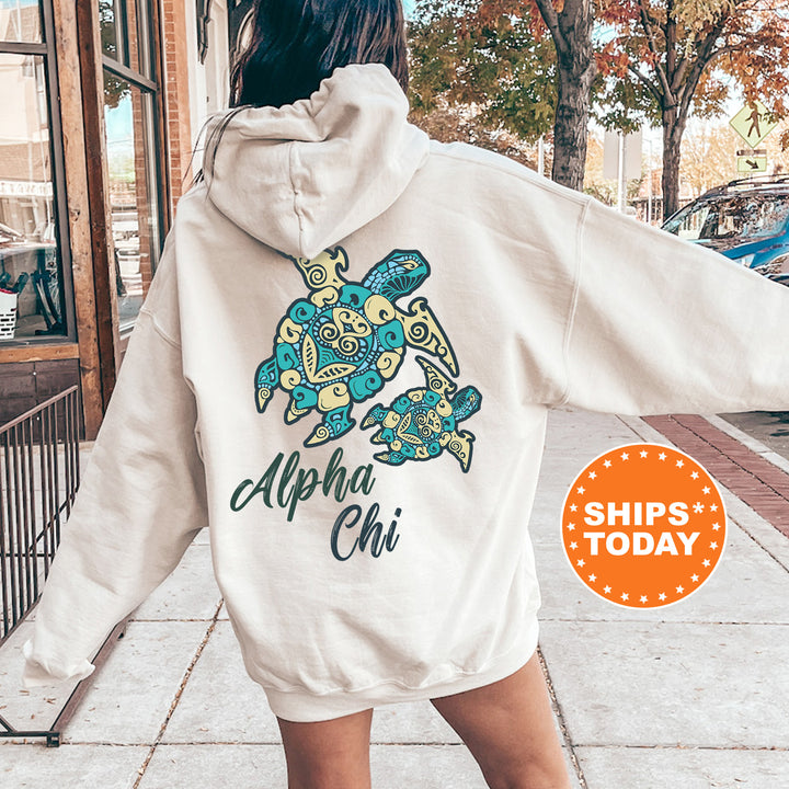 A person wearing a white hoodie with a graphic of a turtle and the text "Alpha Chi" printed on it, standing on a sidewalk.