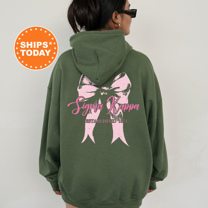 a woman wearing a green sweatshirt with a pink bow on it