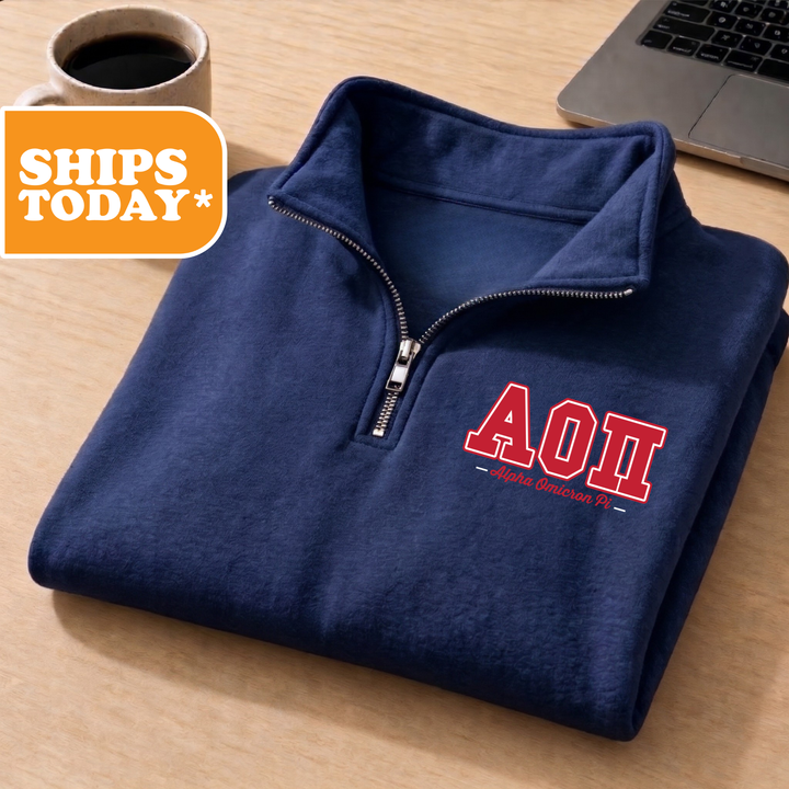 A navy blue zip-up jacket with the letters "AOI" printed on the front, placed on a wooden surface next to a laptop.