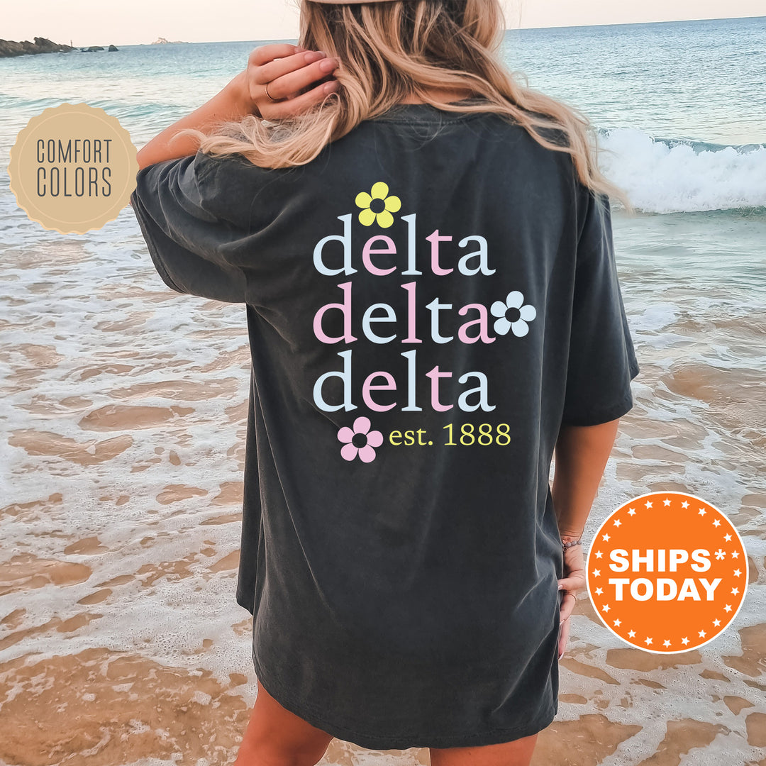 a woman standing on a beach wearing a black delta delta delta shirt