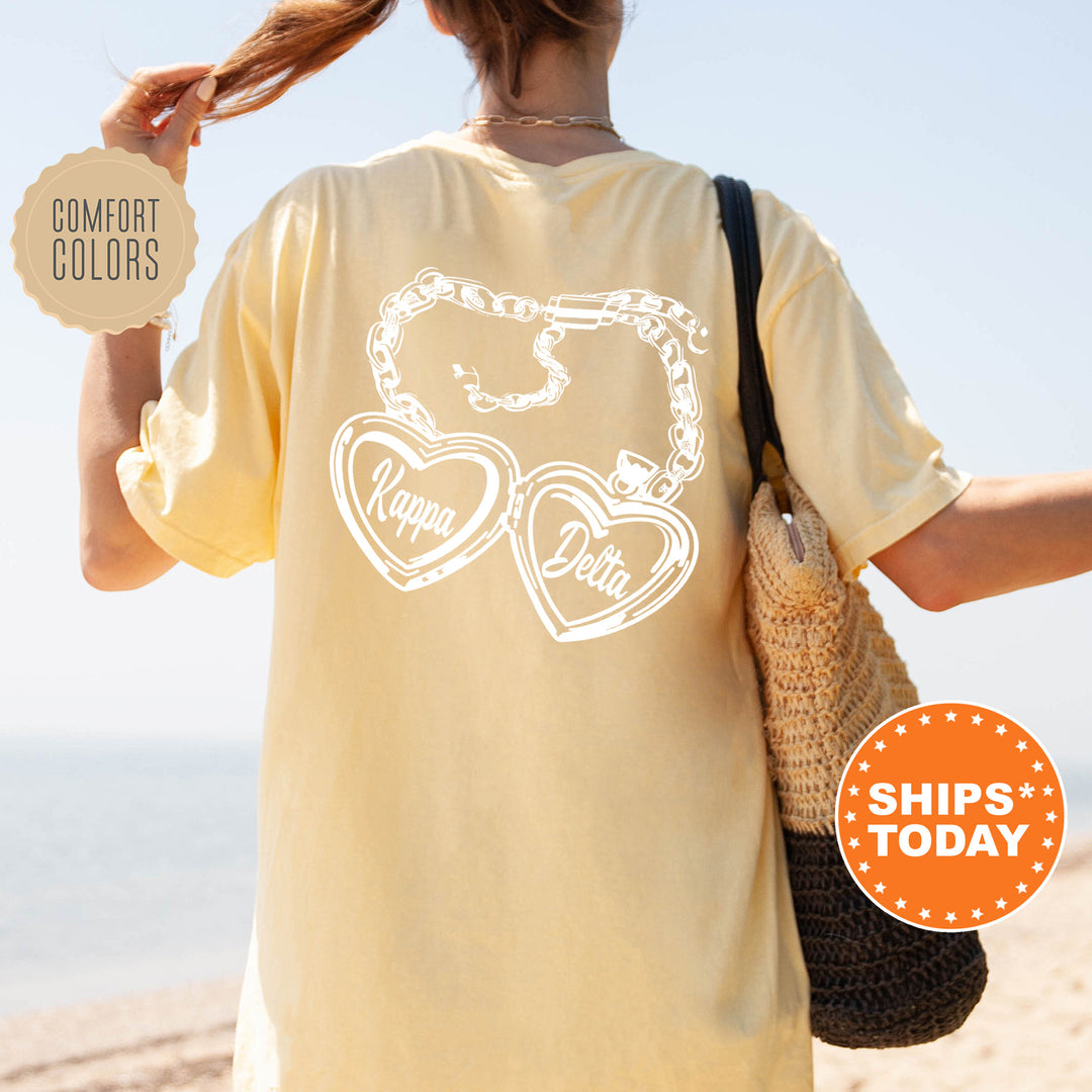 A woman wearing a yellow t-shirt with a graphic design on the back, standing on a beach with her hair in a ponytail.