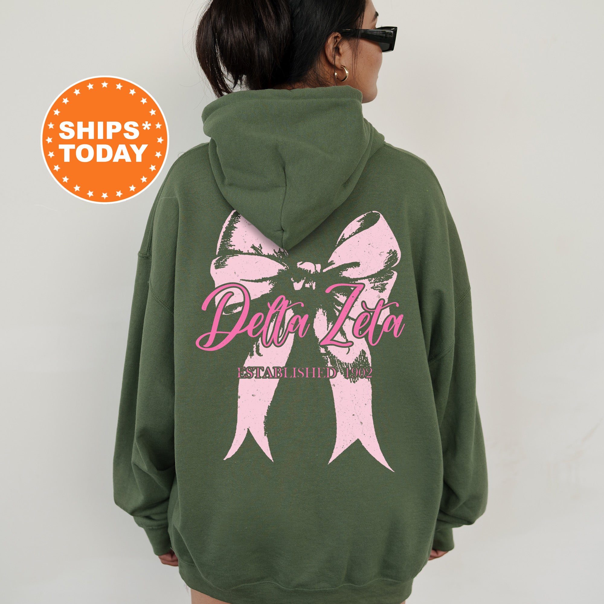 a woman wearing a green hoodie with a pink bow on it