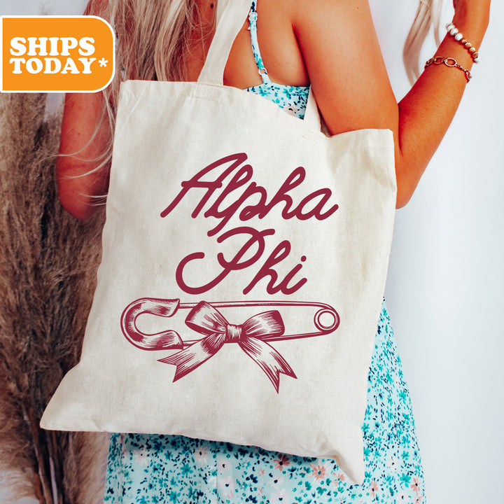 a woman holding a tote bag with a ribbon on it