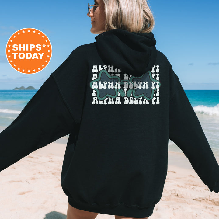 a woman in a black hoodie is walking on the beach