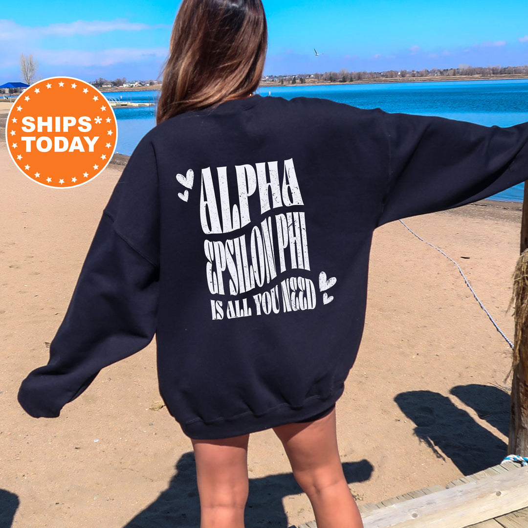 a woman standing on a beach wearing a sweatshirt