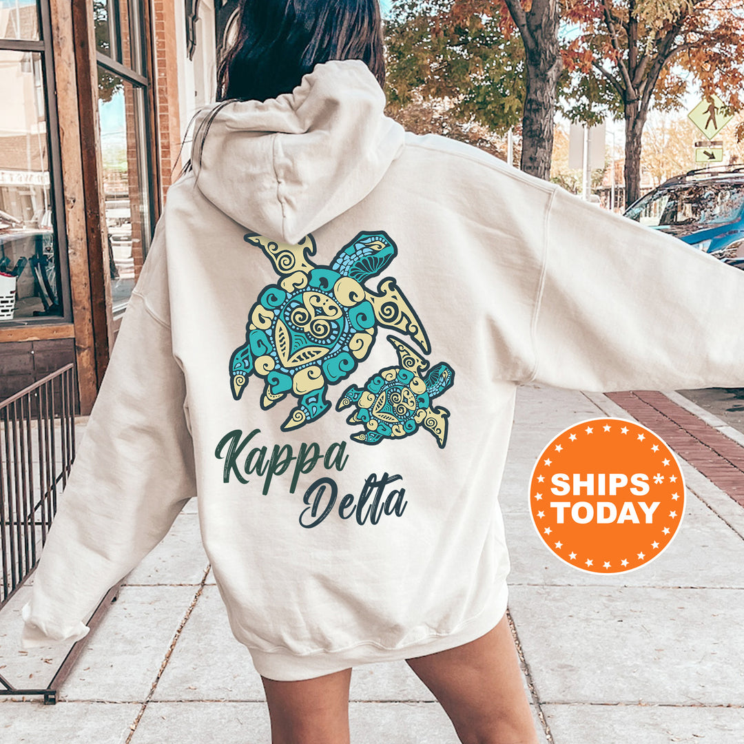 A person wearing a white hoodie with a colorful turtle design and text on the back, standing on a sidewalk.