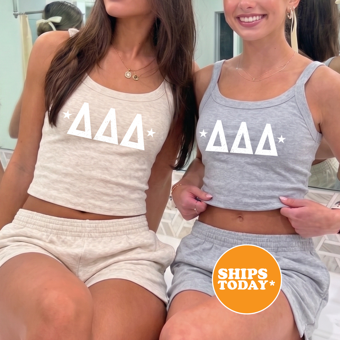 Two women wearing matching tank tops with the Delta Kappa Delta logo, posing together in front of a mirror.