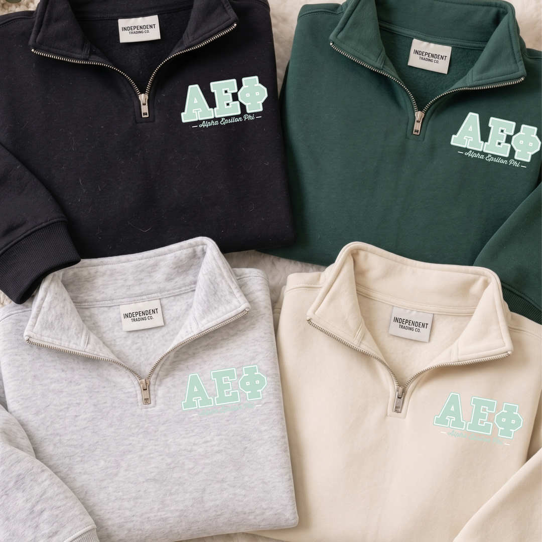 four tops, each with a zipper and a logo, arranged in a row.