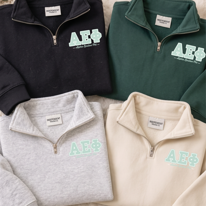 four tops, each with a zipper and a logo, arranged in a row.