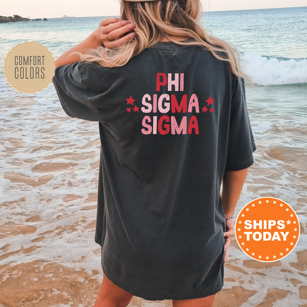 a woman standing on a beach wearing a phi sigma shirt