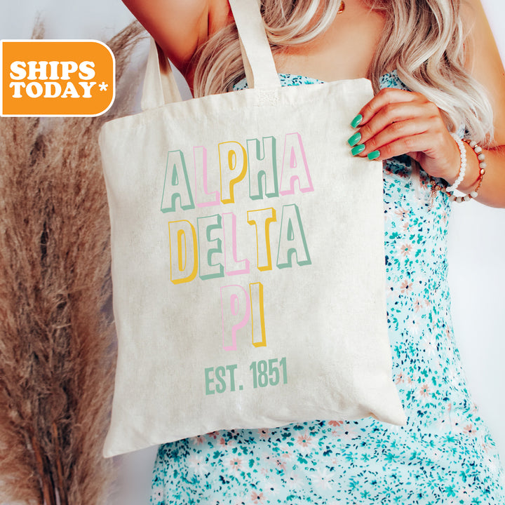 a woman holding a tote bag with the words alpha delta on it