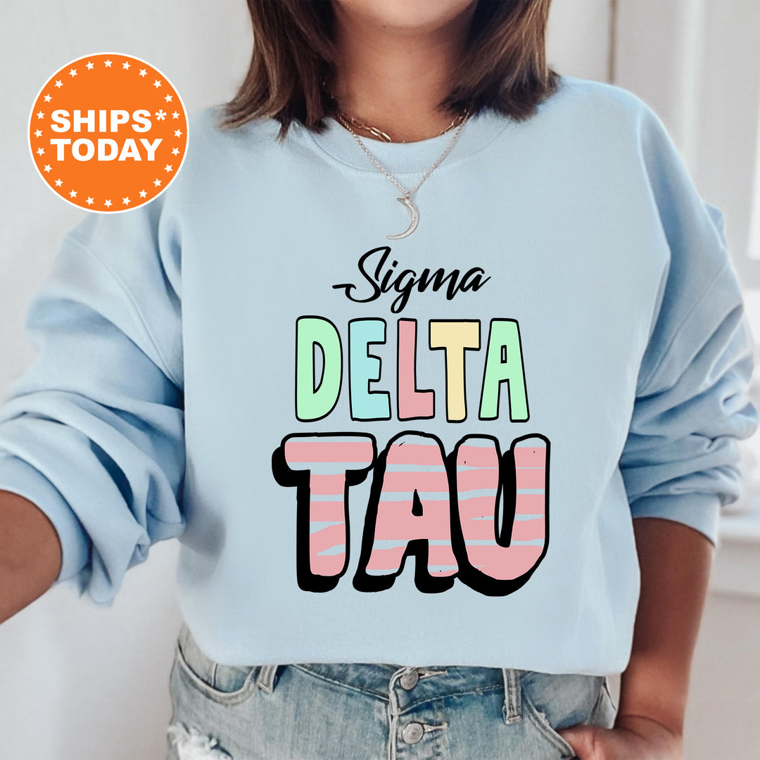 a woman wearing a blue sweatshirt with the words stigmaa delta tau on it