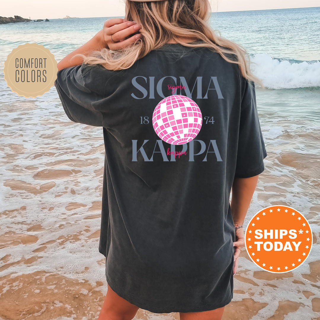 a woman standing on a beach wearing a black shirt