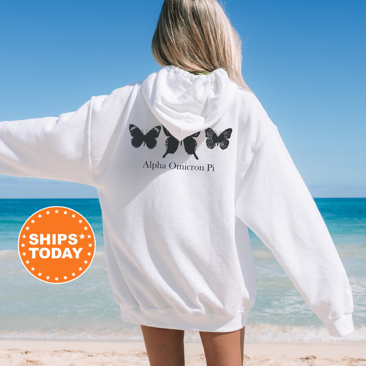 a woman standing on a beach wearing a white sweatshirt