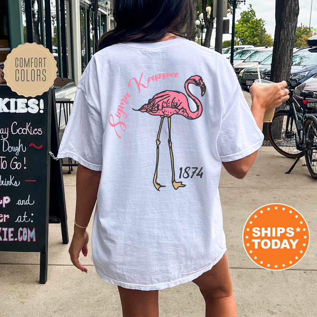 a woman walking down a sidewalk with a pink flamingo on her shirt