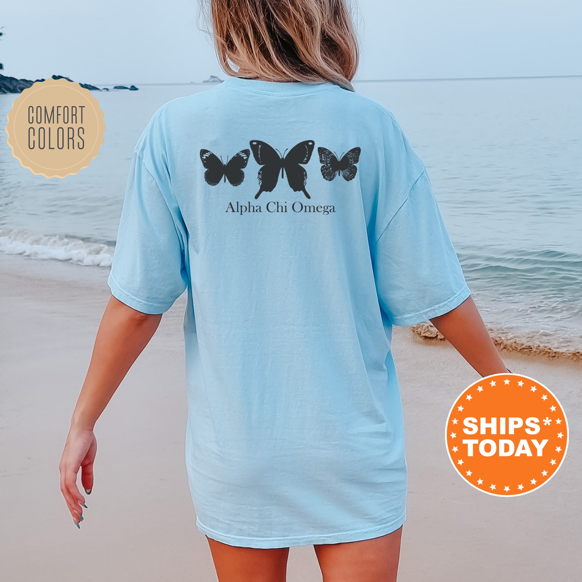 a woman walking on the beach with a butterfly t - shirt on