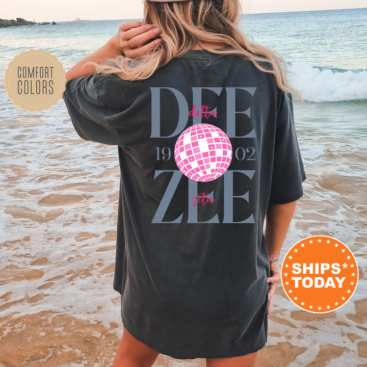 a woman standing on a beach wearing a t - shirt with a disco ball on