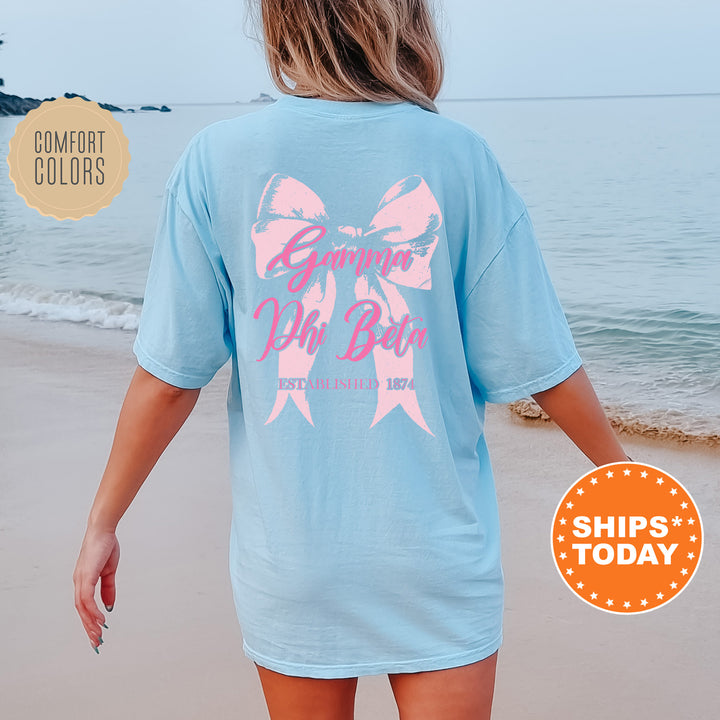 a woman walking on the beach with a pink bow on her shirt