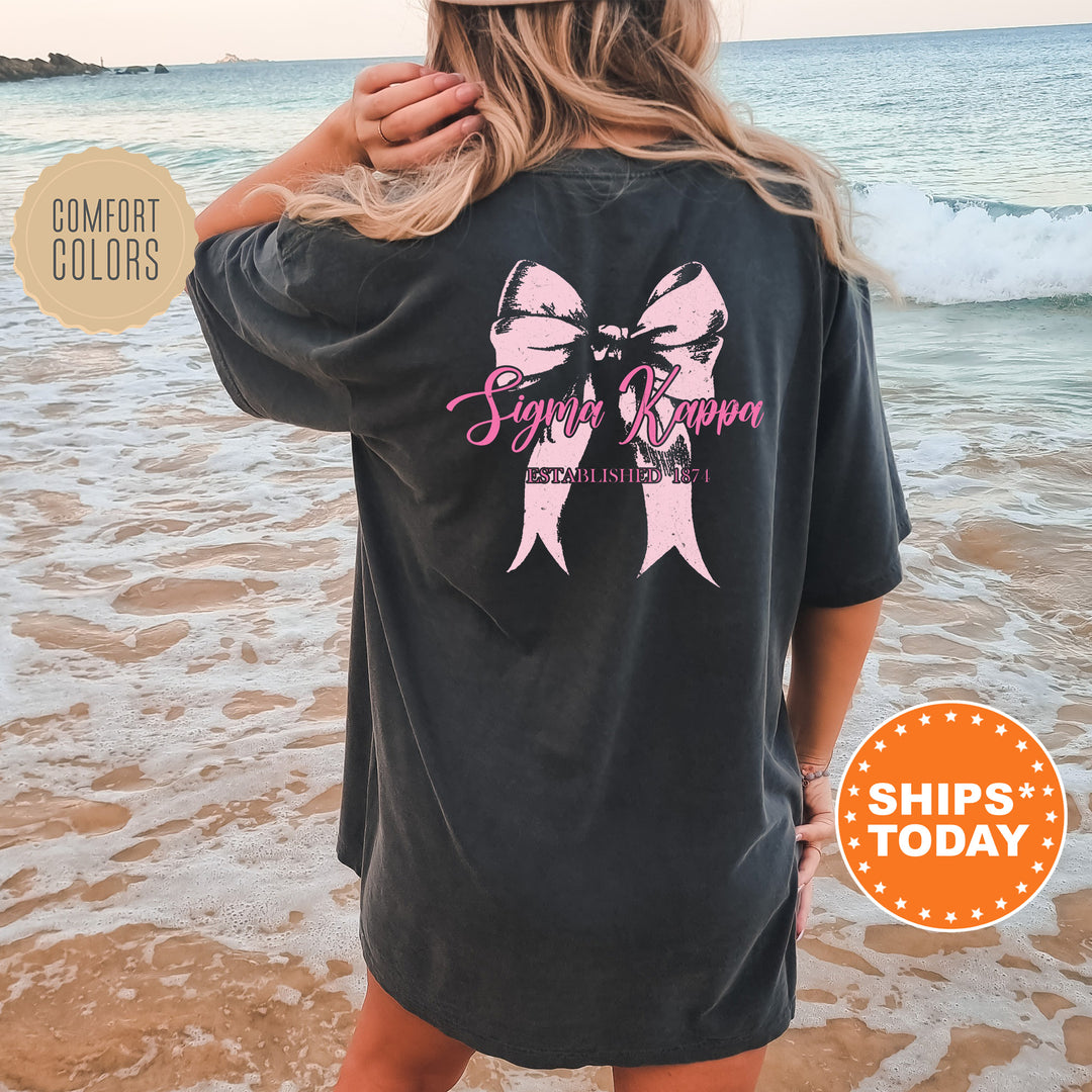 a woman standing on a beach wearing a black shirt with pink ribbon