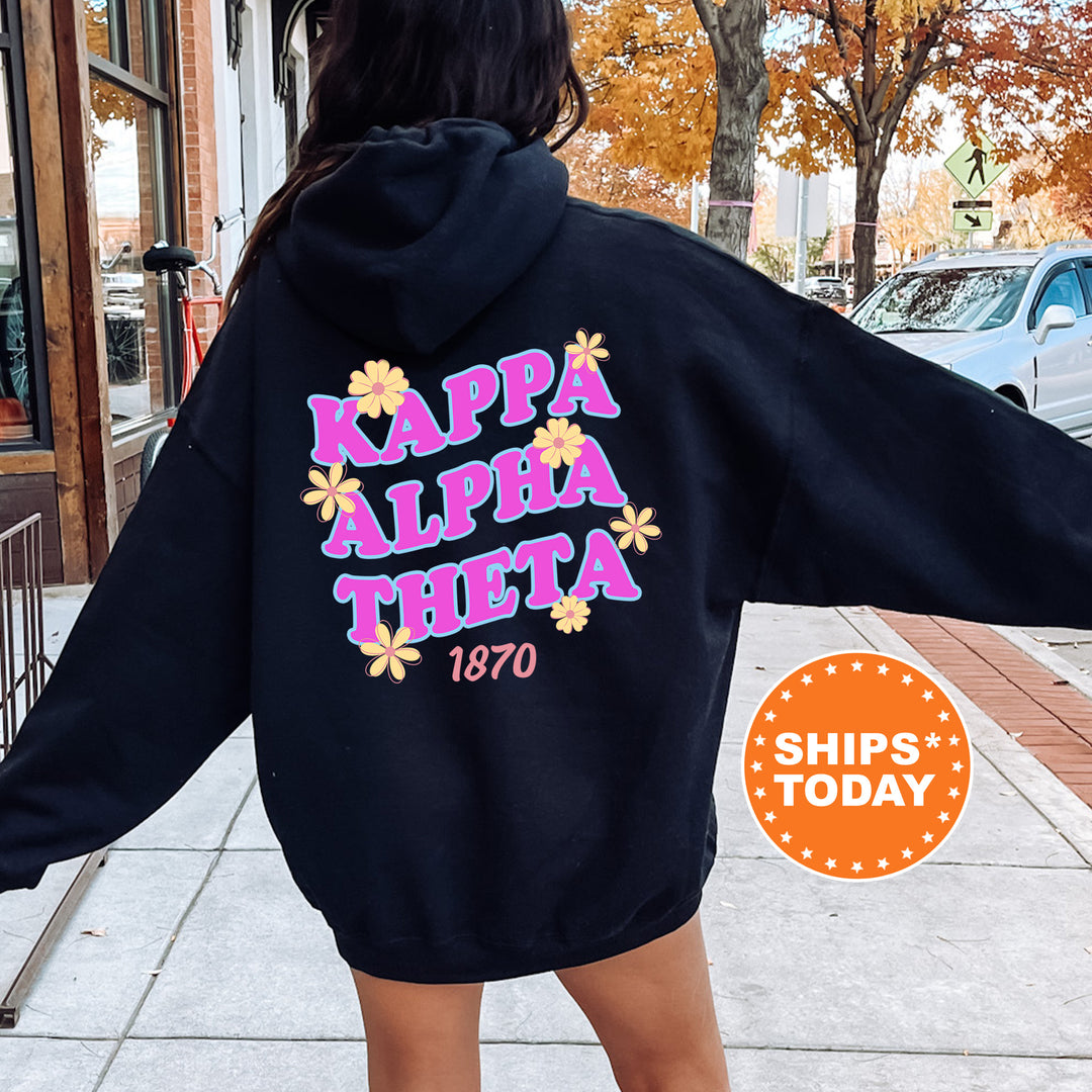 A person wearing a black hoodie with the text " Kappa Alpha Theta" printed on it, standing on a sidewalk.