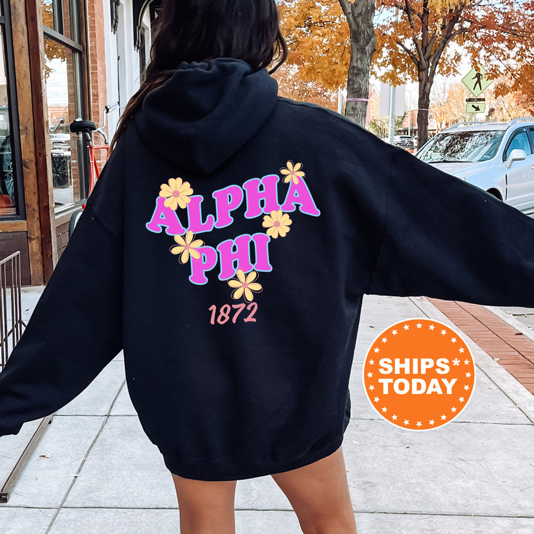 A person wearing a black hoodie with the text "ALPA Phi 1872" printed on it, standing on a sidewalk with a car and a building in the background.