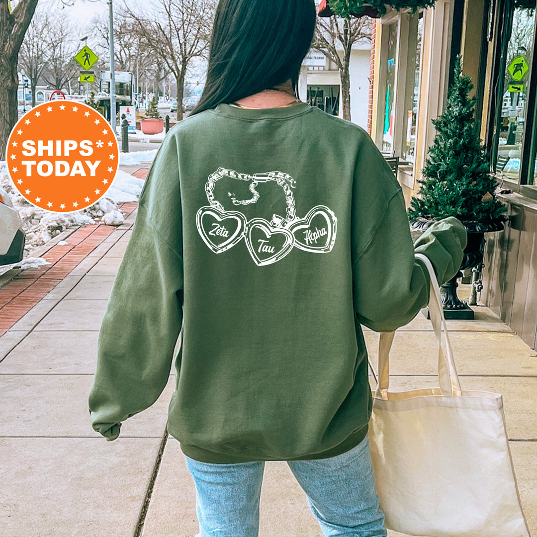 A woman wearing a green sweatshirt with a graphic design on the back is walking down a city street, carrying a white bag.