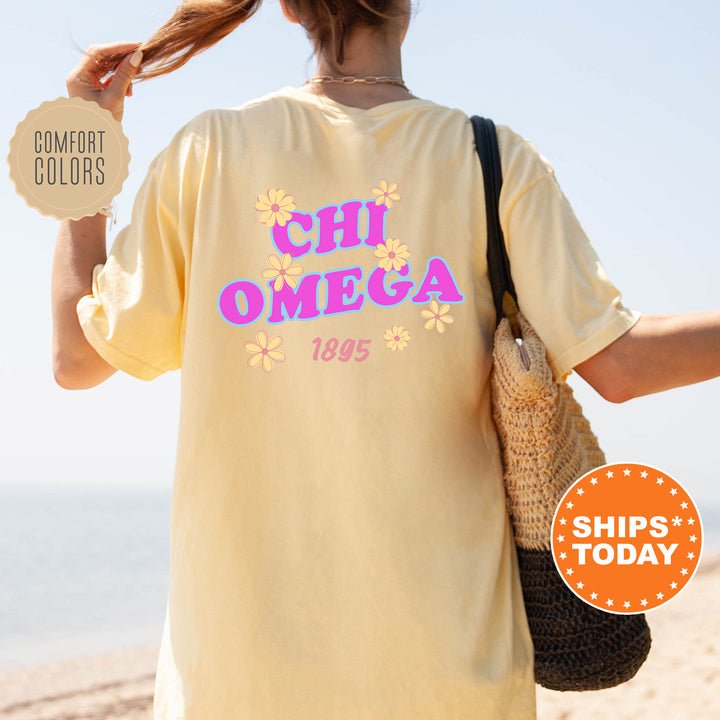 A person wearing a yellow t-shirt with the text "CHI OMEGA 1895" printed on it, standing on a beach.