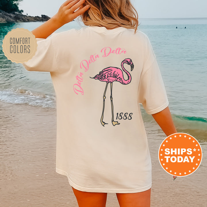 a woman standing on a beach wearing a pink flamingo t - shirt