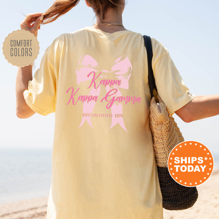 a woman is walking on the beach with a pink ribbon on her shirt