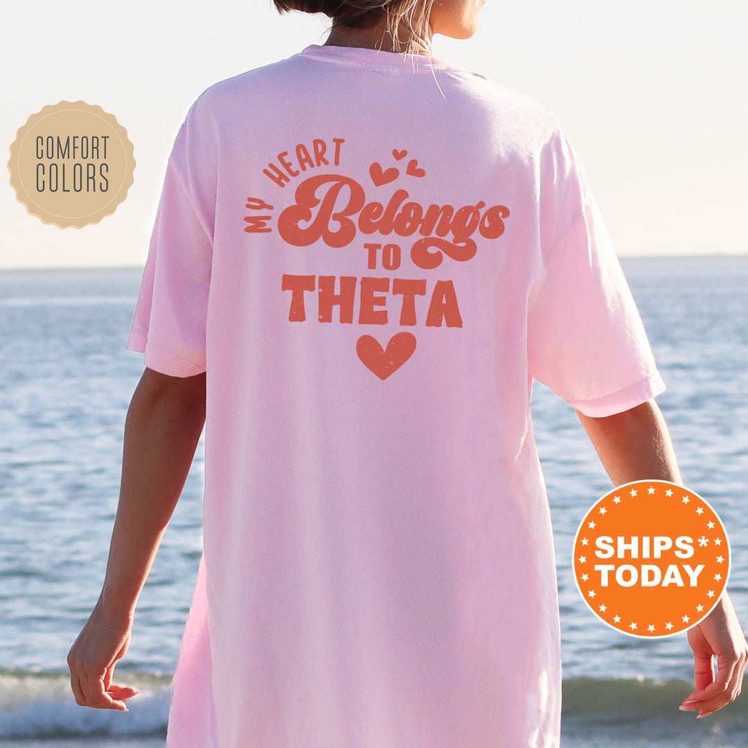 a woman standing on a beach wearing a pink shirt