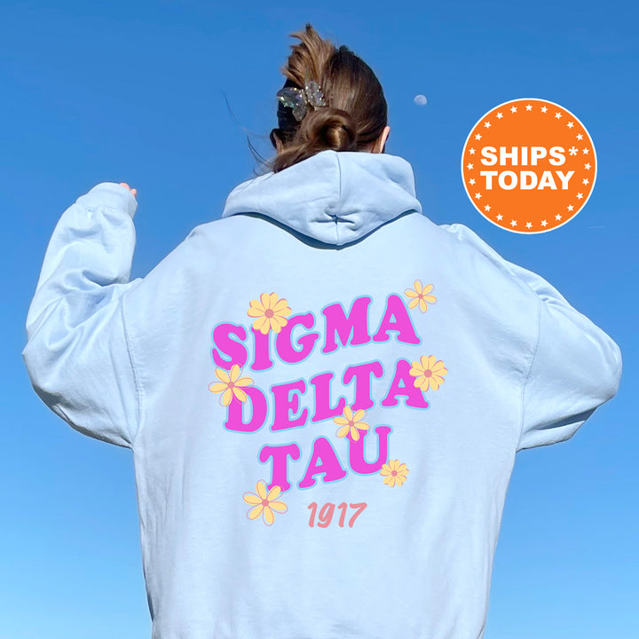 A person wearing a white hoodie with the text "SIGMA DELTA TAU" printed on it, along with a floral design.