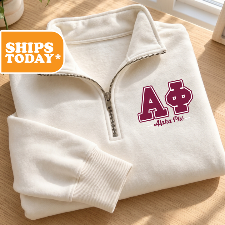 A white zip-up jacket with a purple "A" and "Alpha Phi" logo on the front, placed on a wooden surface.