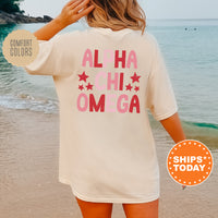 a woman standing on a beach wearing a t - shirt that says alha chi