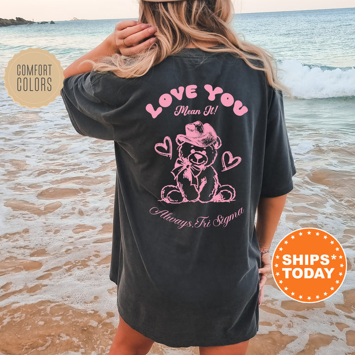 a woman standing on the beach wearing a love you shirt