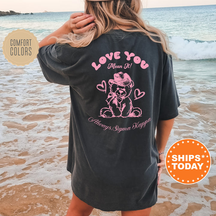 a woman standing on the beach wearing a love you shirt