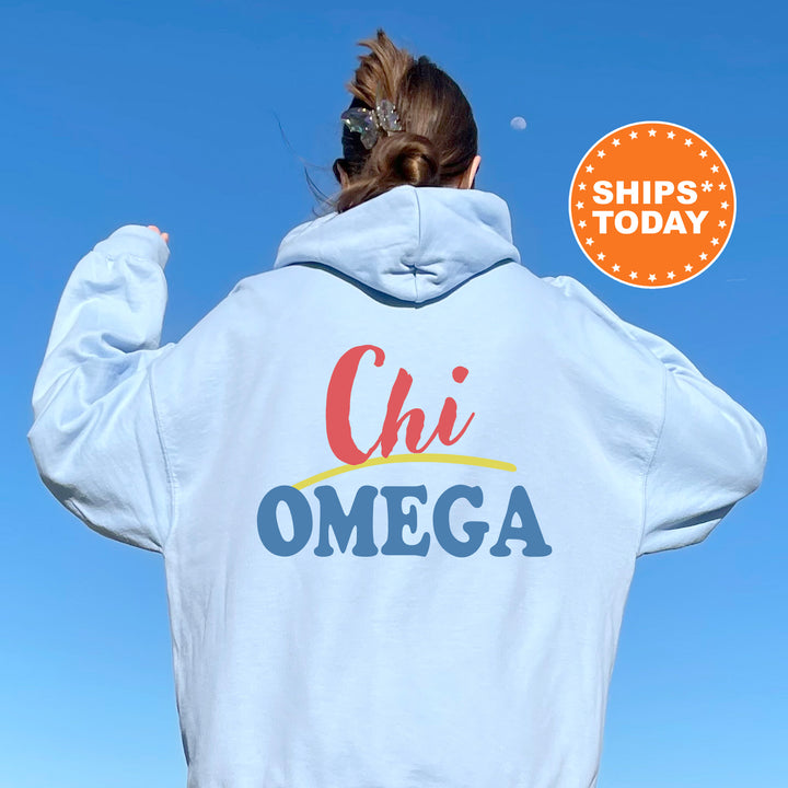 A person wearing a white hoodie with the text "Chi Omega" printed on it, standing against a clear blue sky.