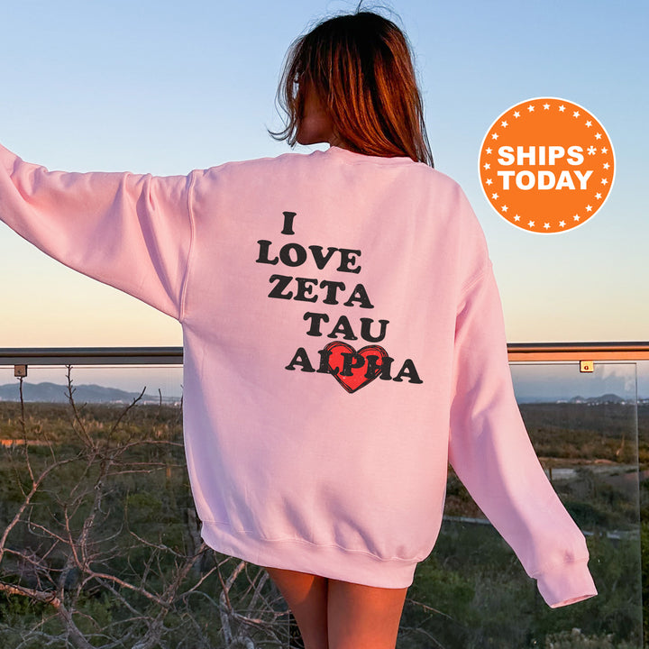 a woman wearing a pink sweatshirt with the words i love zeta tau alpa