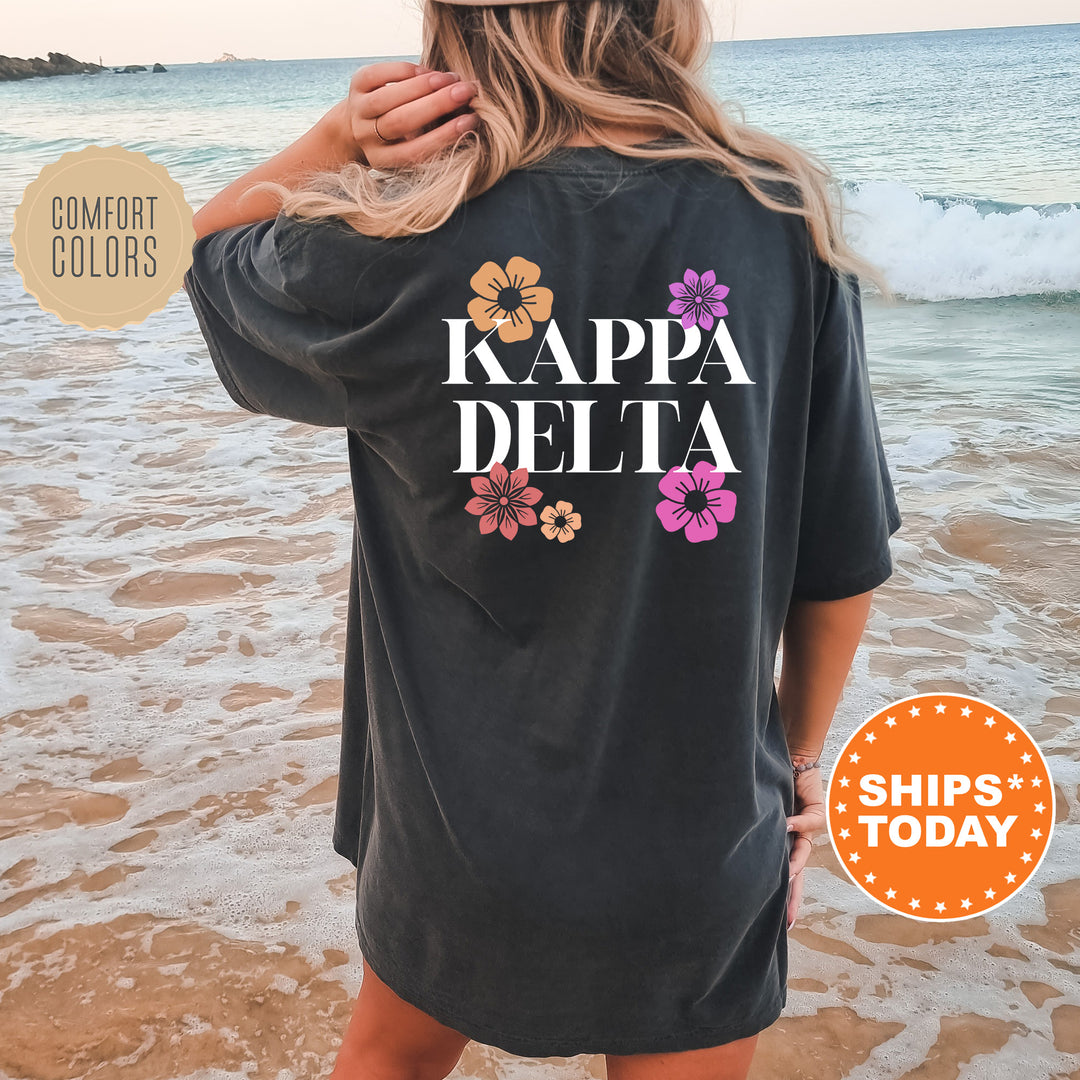 a woman standing on a beach wearing a black kapa delta shirt