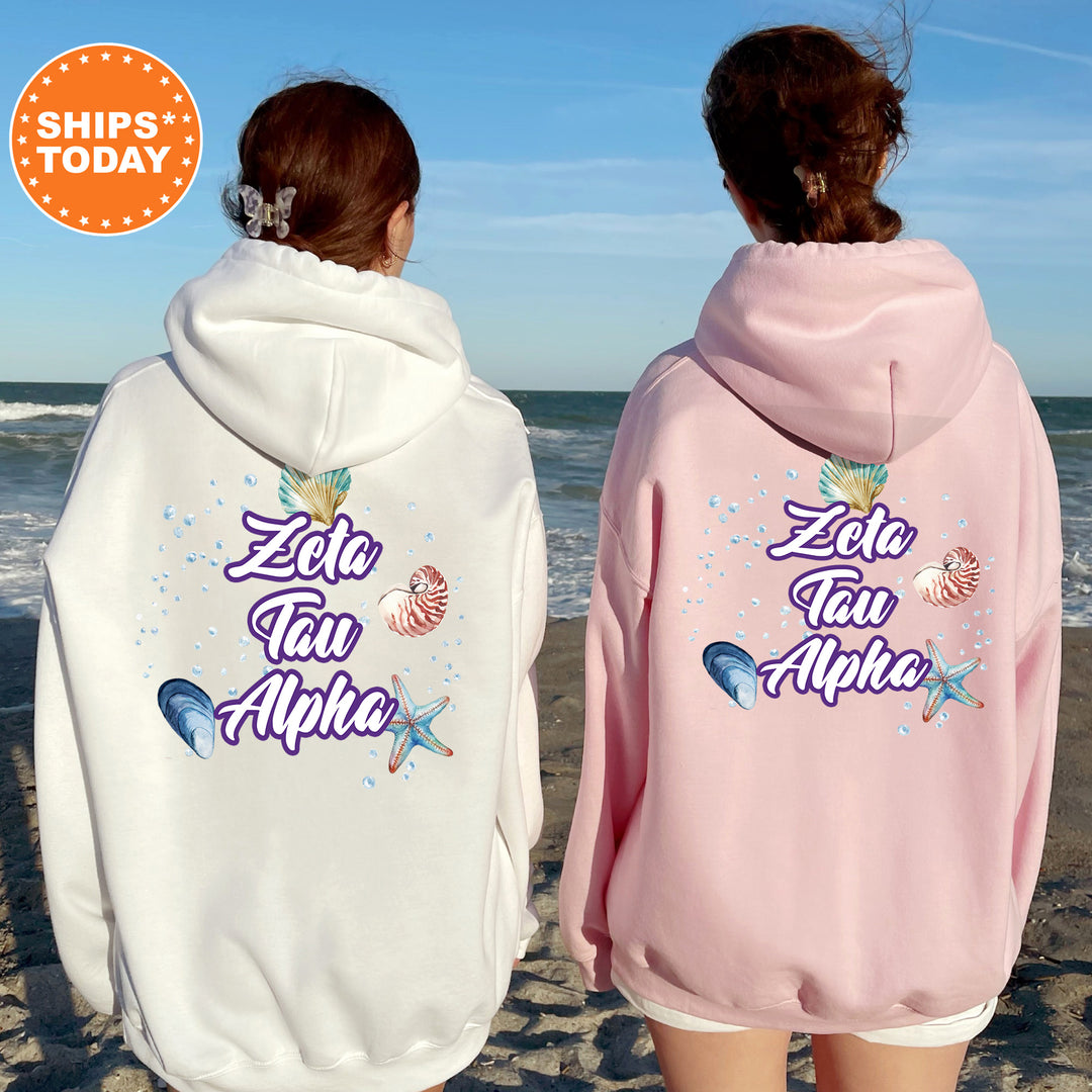 two women wearing matching hoodies on the beach