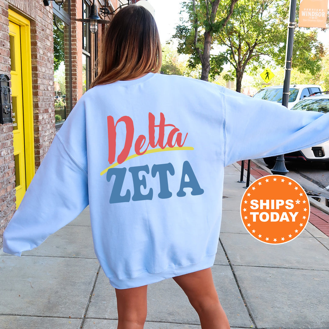 A woman wearing a blue sweatshirt with the text "Delta Zeta" printed on it, standing on a sidewalk.