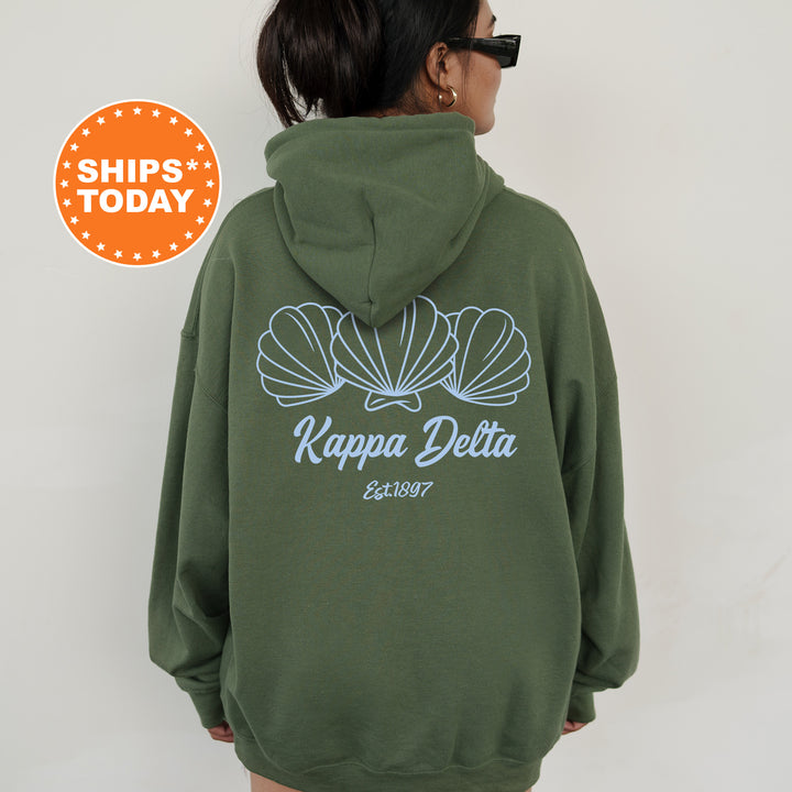 A person wearing a green hoodie with a graphic design of three shells on the back.