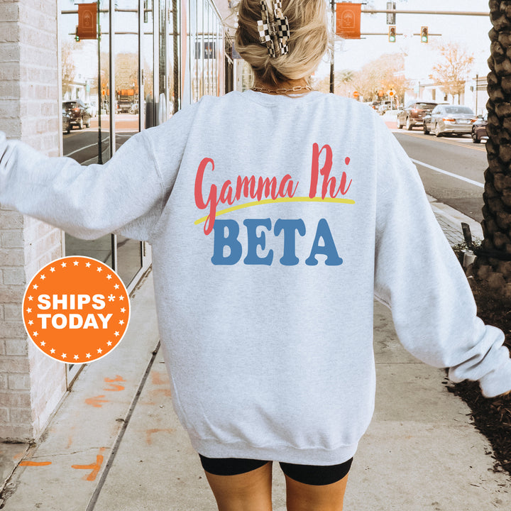 A person wearing a white sweatshirt with the text "Gamma Phi Beta" printed on it, standing on a sidewalk with a city street in the background.