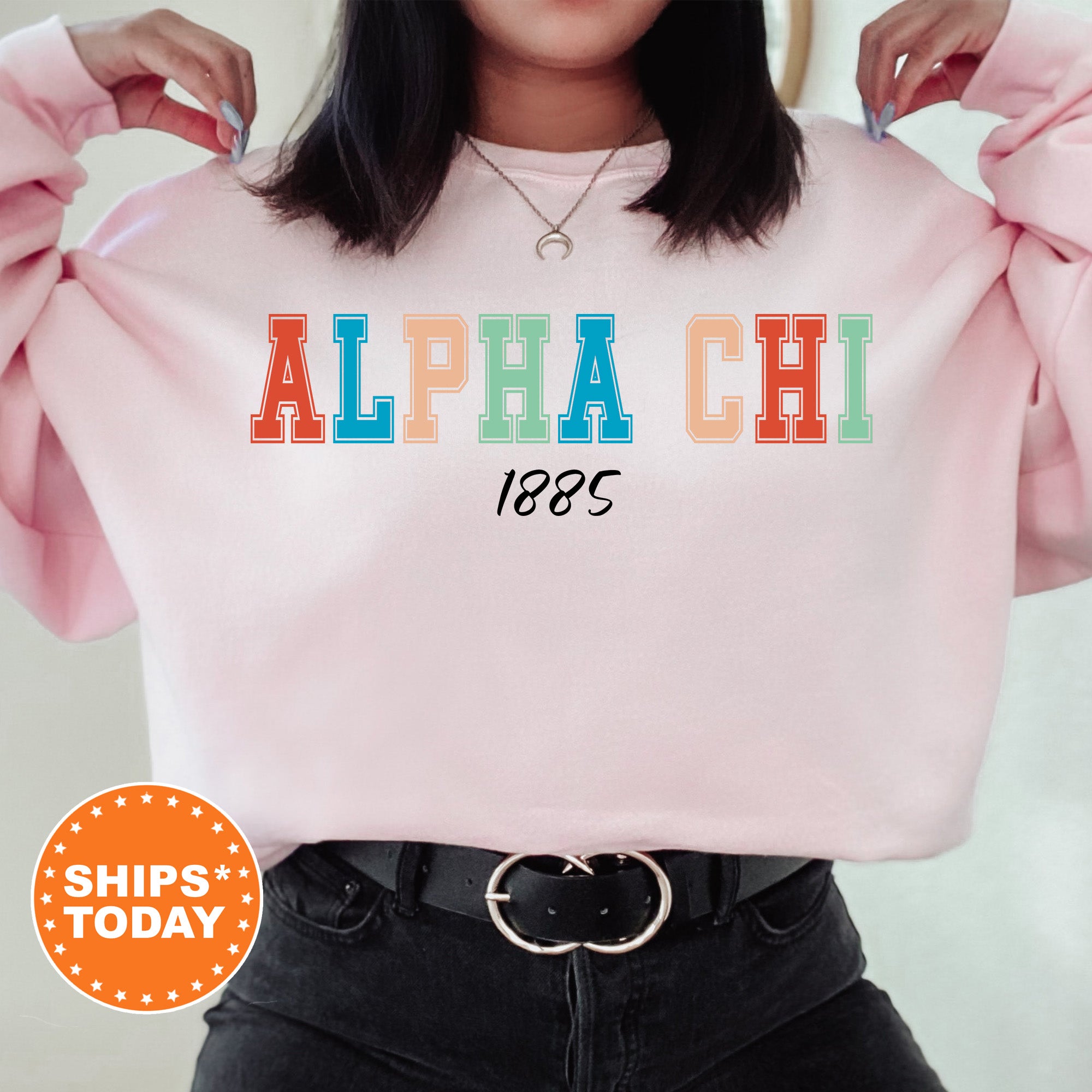 a woman wearing a pink sweatshirt with the word alpha chi printed on it
