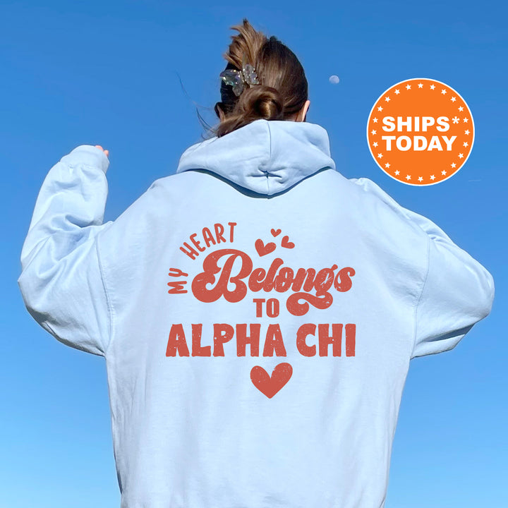 a woman wearing a white hoodie with the words heart belongs to alpha chi