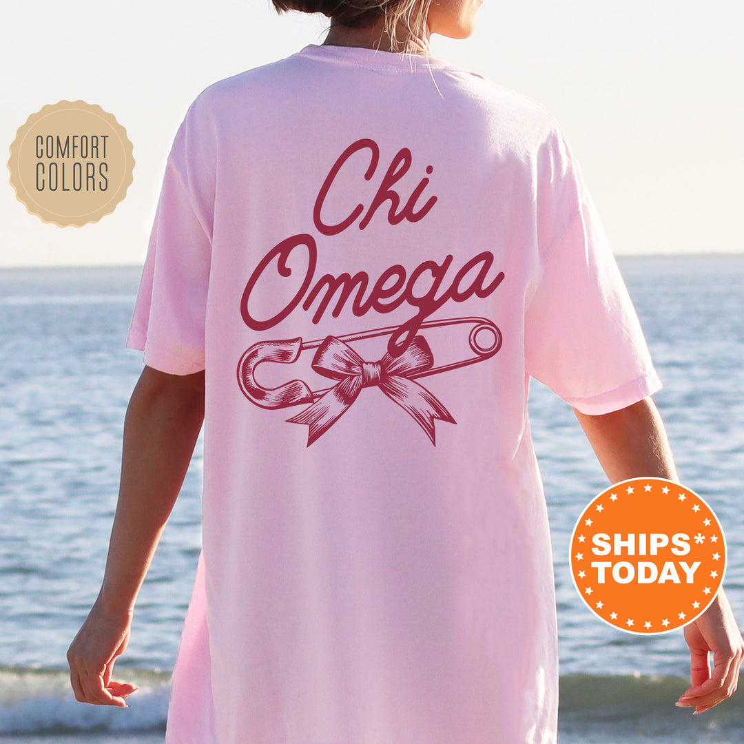 a woman wearing a pink shirt with the words chi omega on it