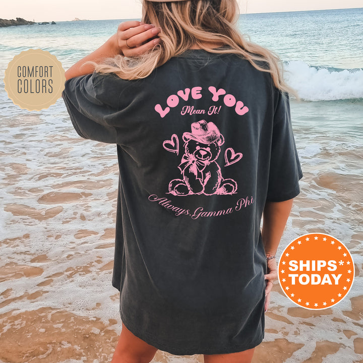 a woman standing on the beach wearing a love you shirt