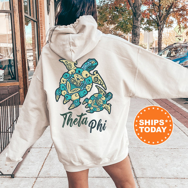 A person wearing a white hoodie with a colorful turtle design and text on the back is standing on a sidewalk.