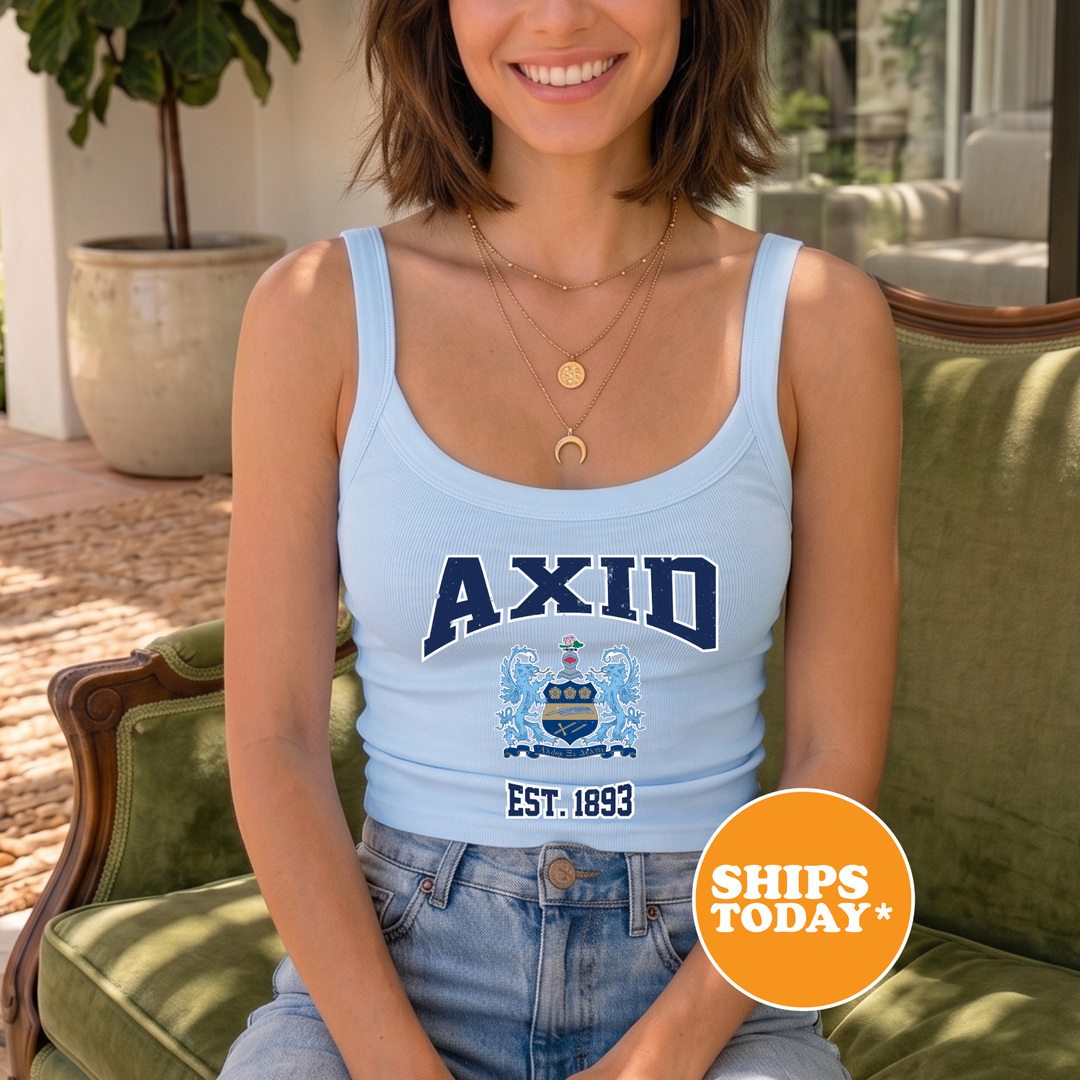 A woman wearing a light blue tank top with the word "AXID" printed on it, sitting on a green chair.